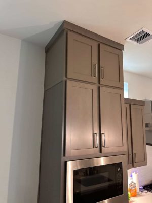Matching painted shaker upper cabinetry in the kitchen above the microwave